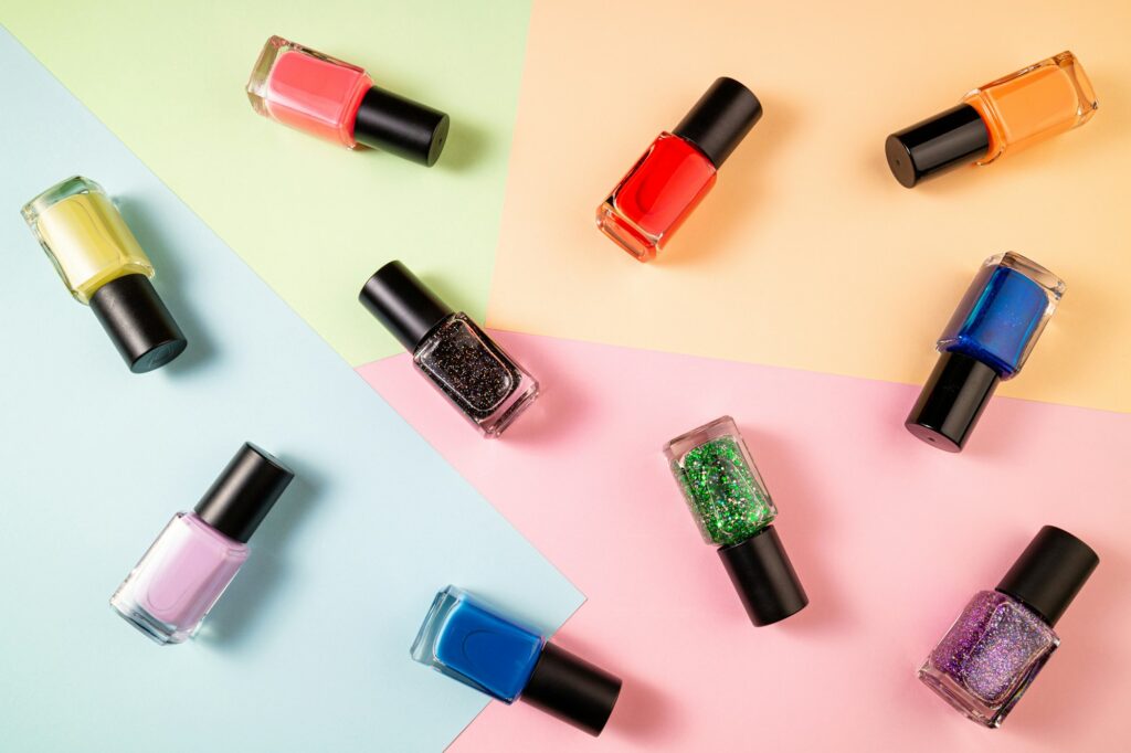 Pattern of various nail polish bottle on color background. Stylish trendy nail polish